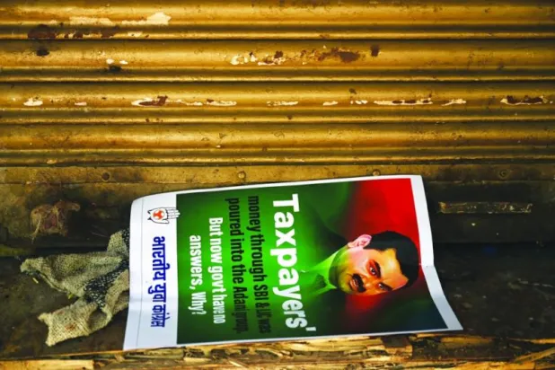 لافتة لرجل الأعمال غوتام أداني على الأرض خلال احتجاجات في نيودلهي يوم 6 فبراير 2023 تطالب بالتحقيق في مزاعم احتيال شركاته (أ.ف.ب)