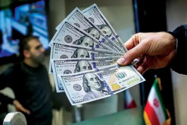 A man raises six 100-dollar bills in his hand at an exchange shop in Tehran (Echo Iran)