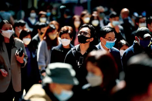 يضعون الكمامات في أحد شوارع هونغ كونغ أمس (أ.ف.ب)