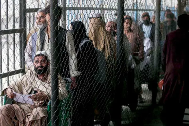 أفغان ينتظرون خلف ممر مسيَّج قبل أن يعبروا إلى باكستان عبر معبر تورخام الحدودي بين أفغانستان وباكستان في مقاطعة ننجرهار (أ.ف.ب)