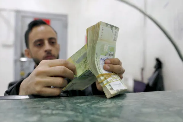 عامل يعد النقود في أحد محلات الصرافة بصنعاء (إ.ب.أ)
