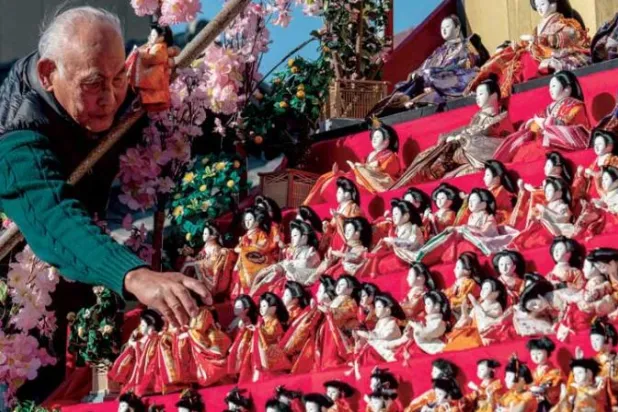 ياباني ينسق دمى تقليدية خلال احتفال محلي بأحد المعابد (ا ف ب)