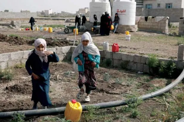 يمنيات يجمعن المياه من أنبوب الري بجوار الخزانات الفارغة في ضواحي صنعاء (إ.ب.أ)