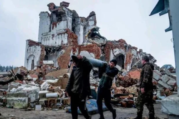 گزشتہ روز مشرقی یوکرین کے دونیتسک کے علاقے میں گاؤں دولیما پر بمباری میں تباہ ہونے والے چرچ کے احاطے کی صفائی کے دوران دو رضاکار میزائل کی باقیات اٹھائے ہوئے ہیں (اے ایف پی)