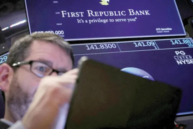 وال اسٹریٹ اسٹاک ایکسچینج کے پچھلے سیشن میں امریکی "فرسٹ ریپبلک بینک" کا لوگو ایک تاجر کے پیچھے اسکرین پر نظر آ رہا ہے (رائٹرز)