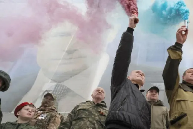 یوکرینی جزیرہ نما کریمیا کے الحاق کی نویں سالگرہ کے موقع پر کل شہر یالٹا میں پوٹن کی ایک بڑی تصویر والے بینر کے سامنے سے ایک جلوس گزر رہا ہے (رائٹرز)