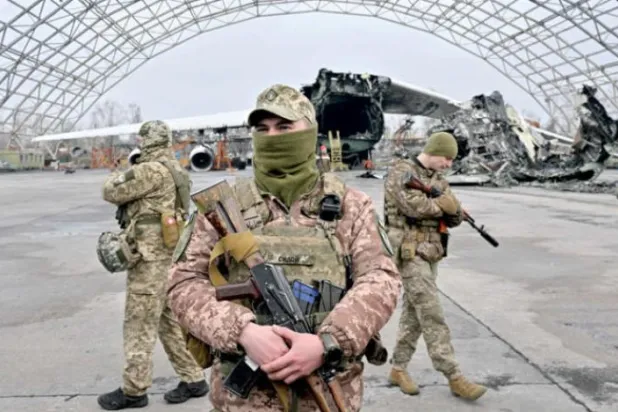 کل کیف کے قریب ایک ہوائی اڈے پر یوکرینی فوج کے اینٹی ڈرون یونٹس کو مشین گنوں سے لیس "پک اپس" کے حوالے کرنے کی تقریب کی فوجی حفاظت کر رہے ہیں... اور روسی حملے میں تباہ ہونے والے "انٹونوف" کارگو طیارے کا ملبہ بھی دکھائی دے رہا ہے (اے ایف پی)