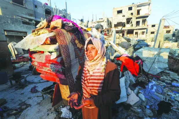 Dün Gazze Şeridi’nin güneyindeki Refah kampında İsrail bombardımanında yıkılan bir evin önünden geçen şoke olmuş Filistinli bir kadın (AFP)