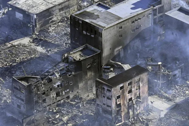 تصاعد الدخان من المنازل التي احترقت عقب الزلزال في واجيما (أ.ب)