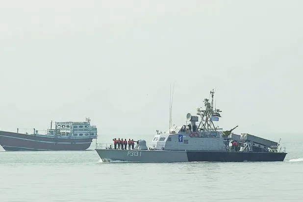 سفن خشبية بالقرب من طراد حربي تابع لـ«الحرس الثوري» خلال مناورات (فارس)