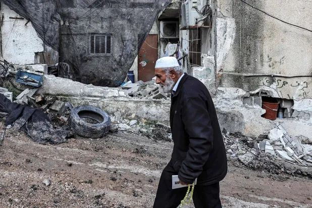 طولکرم شہر کے قریب نور شمس فلسطینی پناہ گزین کیمپ پر اسرائیلی حملے کے بعد ایک بزرگ فلسطینی شخص تباہ شدہ عمارت کے سامنے سے گزر رہا ہے (اے ایف پی)