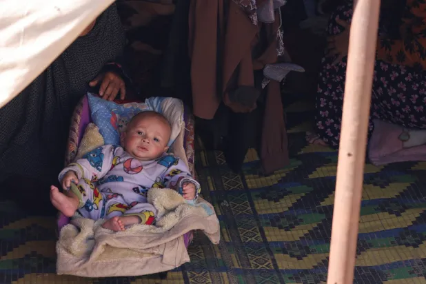 طفل في خيمة عائلة نازحة إلى رفح هرباً من ضربات إسرائيل على قطاع غزة (رويترز)