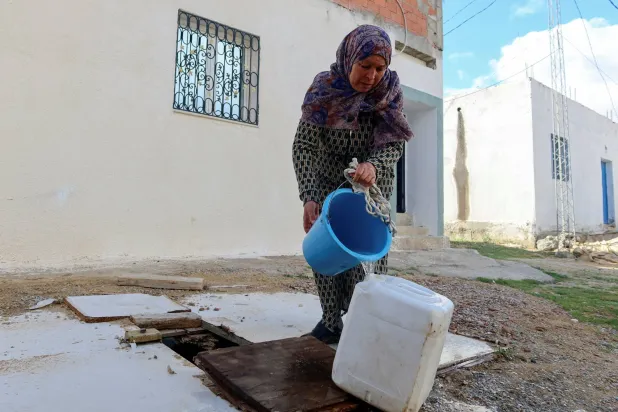 تونسية تملأ غالون الماء بعد تقطع صبيب المياه الشروب في بلدتها بنابلس (رويترز)