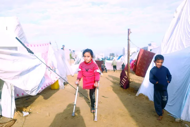 کل جنوبی غزہ کی پٹی کے شہر رفح میں بے گھر افراد کے کیمپ میں ایک فلسطینی لڑکی بیساکھی کی مدد سے چل رہی ہے (روئٹرز)