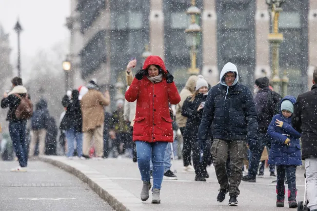 أشخاص يسيرون وسط تساقط الثلوج على جسر وستمنستر في لندن (إ.ب.أ)