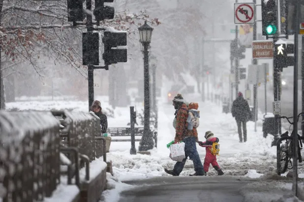 مشاة في شارع يكسوه الثلج في مدينة أيوا سيتي بولاية أيوا الأميركية (أ.ف.ب)