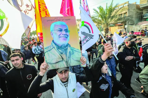 عراقی دھڑوں کے حامیوں کا ایک گروپ بغداد میں انجینئر کی تصویر اور "عوامی فورسز" کا نشان اٹھائے ہوئے ہیں (اے ایف پی)