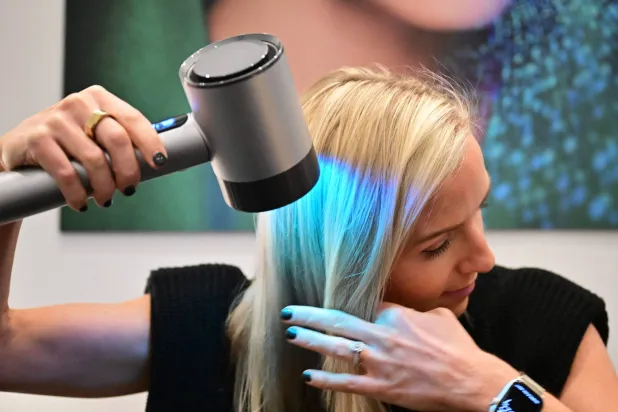 سيدة تستعرض كيفية استخدام مجفف الشعر Airlight Pro من لوريال والذي يستعمل تقنية الأشعة دون الحمراء (أ.ف.ب)