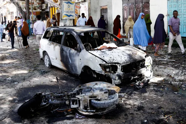 صوماليون يمرون قرب مكان الحادث بعد تفجير انتحاري بالقرب من مطعم في منطقة حمروين في مقديشو (الصومال) الثلاثاء (رويترز)