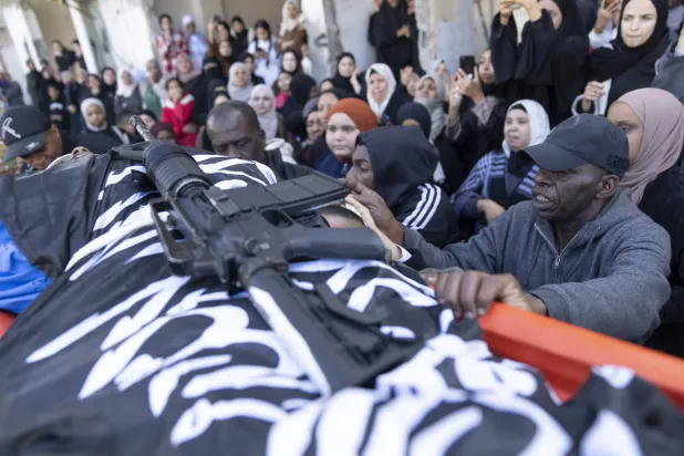 بندقية فوق جثمان شاب قتلته القوات الإسرائيلية في مخيم طولكرم (أ.ب)