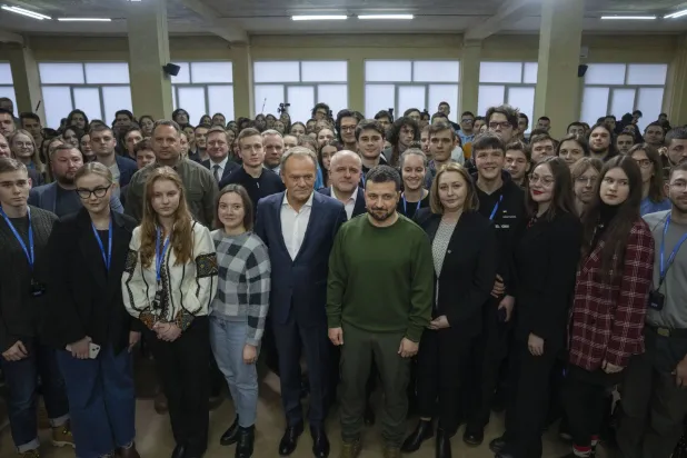 الرئيس الأوكراني فولوديمير زيلينسكي ورئيس الوزراء البولندي دونالد توسك يلتقطان صورة مع طلبة أوكرانيين بعد لقاء في كييف الاثنين (أ.ب)