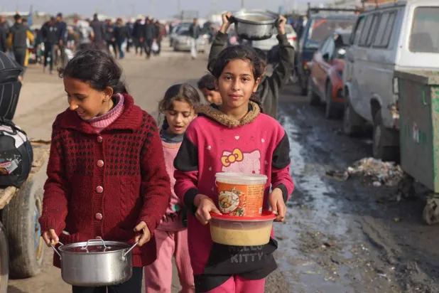 Girls carrying food containers in a temporary camp in Rafah, near the border with Egypt in the southern Gaza Strip. (AFP)