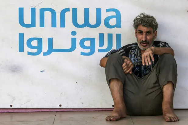 لاجئ فلسطيني بجانب علامة «الأونروا» في مدرسة تديرها الوكالة في صيدا بجنوب لبنان (د.ب.أ)