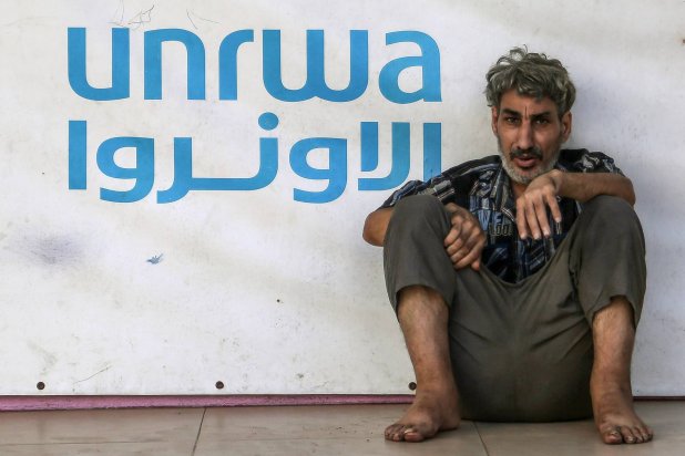 لاجئ فلسطيني بجانب علامة «الأونروا» في مدرسة تديرها الوكالة في صيدا بجنوب لبنان (د.ب.أ)