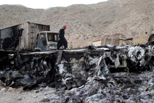رجل يسير على مقطورة شاحنة مدمرة بعد هجوم شنه مسلحون مجهولون في كولبور بالقرب من كويتا بإقليم بلوشستان جنوب غربي باكستان يوم 30 يناير 2024 (رويترز)