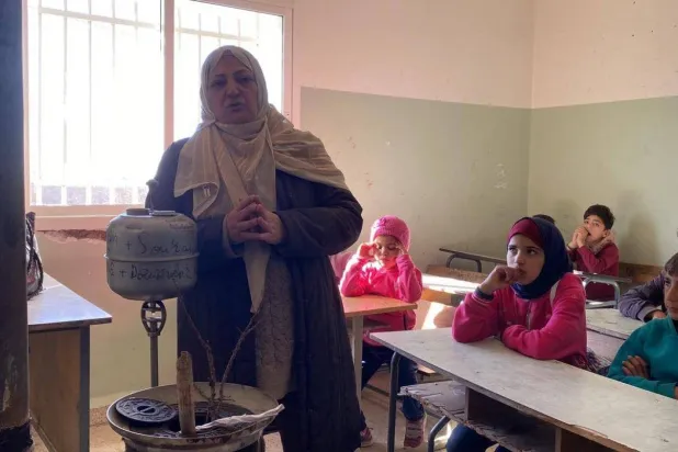 Teacher Salwa Hazeem lights the heater and complains about the smoke emission inside the classroom (Asharq Al-Awsat)