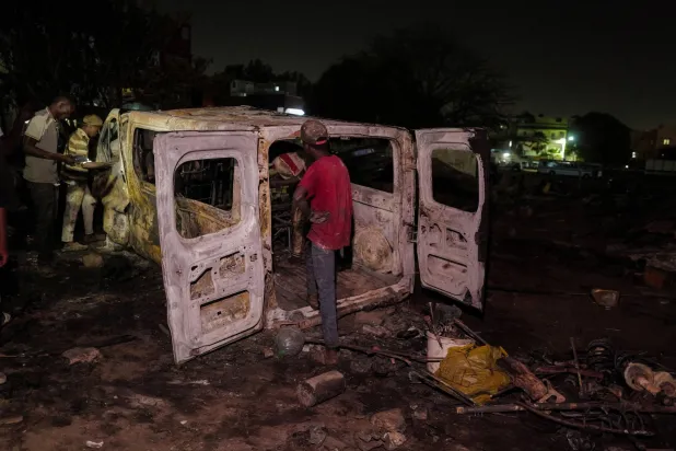 أشخاص يتفقدون شاحنة محترقة في ورشة لتصليح السيارات اشتعلت فيها النيران في داكار 6 فبراير 2024 (رويترز)