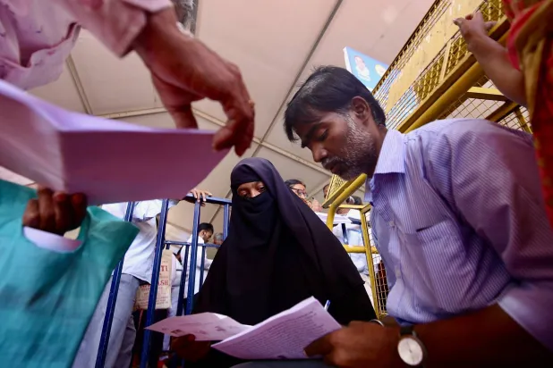 أشخاص يقومون بملء نماذج الطلبات لتقديم شكاواهم خلال حدث في بنغالور بالهند (إ.ب.أ)