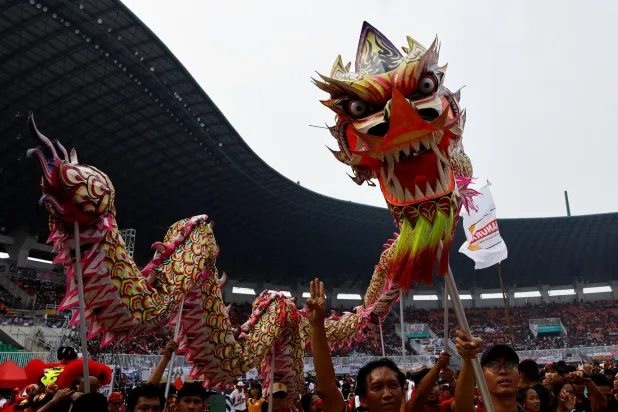 أشخاص يؤدون رقصة التنين قبل حلول العام القمري الصيني الجديد (رويترز)