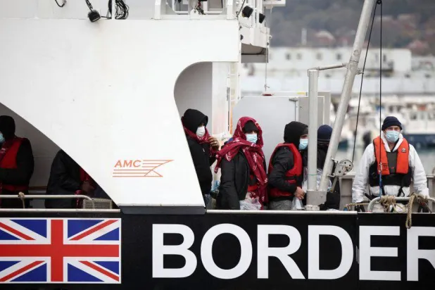 يتم إحضار المهاجرين إلى الشاطئ على متن سفينة تابعة لقوات الحدود بعد عبور القناة في ميناء دوفر ببريطانيا (رويترز)
