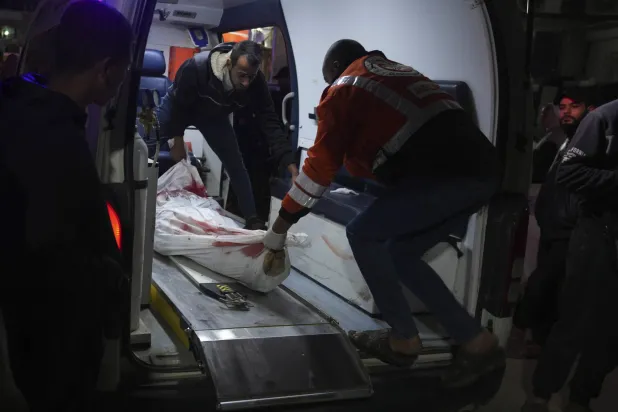 مسعفون يقومون بنقل جثث الفلسطينيين الذين قتلوا في القصف الإسرائيلي على مخيم النصيرات للاجئين في قطاع غزة في مستشفى الأقصى في دير البلح (أ.ب)