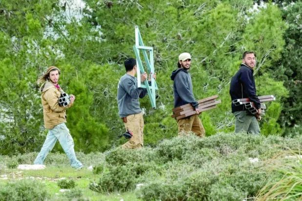 مستوطنون ينقلون مواد بناء باتجاه بؤرة استيطانية في قرية الجبعة بالضفة يناير 2023 (أ.ف.ب)