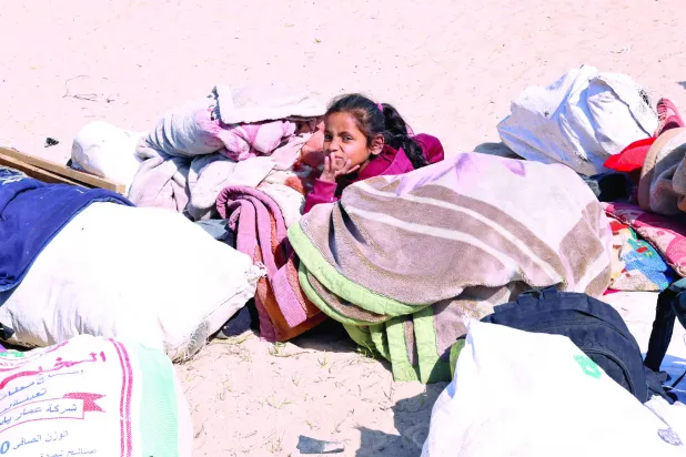 
طفلة نازحة تجلس وسط أغطية ومستلزمات أخرى في رفح بجنوب قطاع غزة أمس (رويترز)