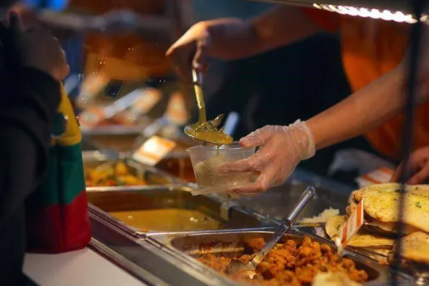 عامل في مطعم للوجبات السريعة يعد وجبة لأحد العملاء (رويترز)