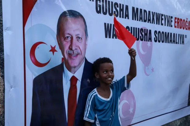 Cumhurbaşkanı Recep Tayyip Erdoğan'ın Cumhurbaşkanlığı seçimlerini kazanmasının ardından resminin önünde Türk bayrağıyla poz veren Somalili bir çocuk, 29 Mayıs 2023 (AFP)