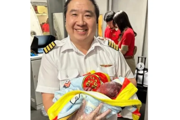 الطيار جاكارين سارانراكسكول يحمل الطفل المولود على متن الطائرة (إنستغرام)