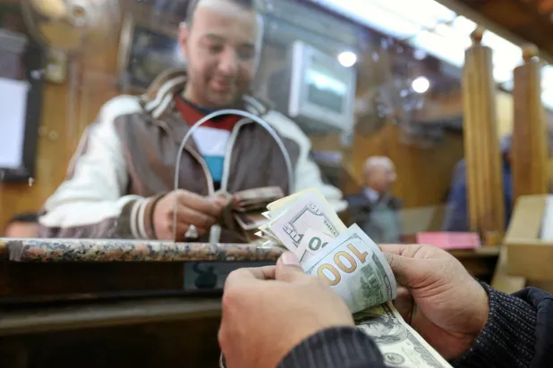 عميل يقوم بتحويل الدولار الأميركي إلى الجنيه المصري (رويترز)