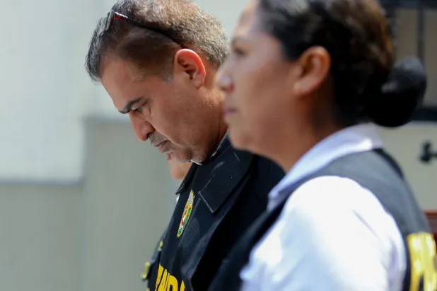 شرطية من بيرو تقتاد عزيزي إلى مركز للتوقيف في بيرو (أ.ب)