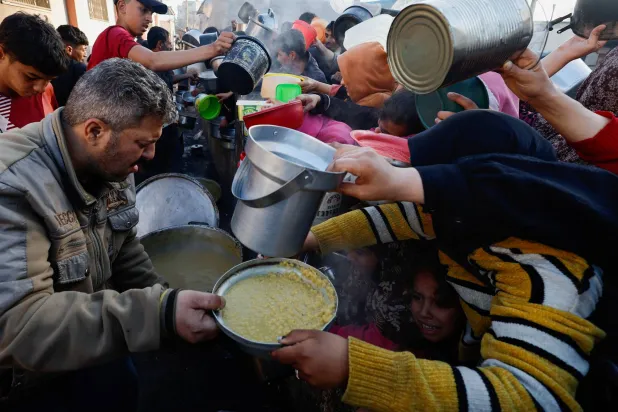 فلسطينيون ينتظرون الحصول على الطعام خلال شهر رمضان وسط النقص الحاد بالمواد الغذائية (رويترز)