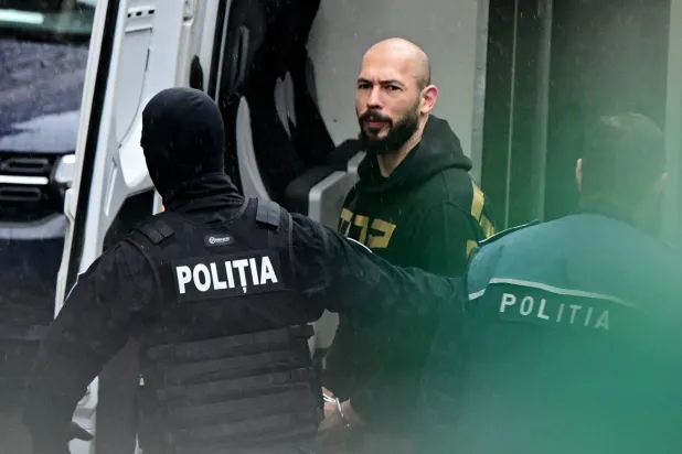 الملاكم البريطاني - الأميركي السابق والمؤثر أندرو تيت محاطاً بعناصر الشرطة خلال اقتياده إلى محكمة الاستئناف في بوخارست (أ.ف.ب)