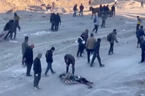 Gazze Şehri'ndeki Al-Rashid Yolu üzerinde yardım beklerken katledilenleri taşıyan Filistinliler (Reuters)