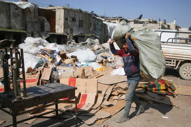 صبي سوري يحمل مواد قابلة لإعادة التدوير ليتم وزنها في مكب للقمامة في محافظة إدلب 14 مارس (أ.ف.ب)