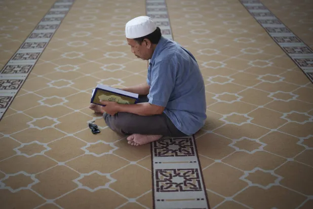 رجل يجلس في المسجد لقراءة القرآن في رمضان المبارك في كوالالمبور بماليزيا (أ.ب)