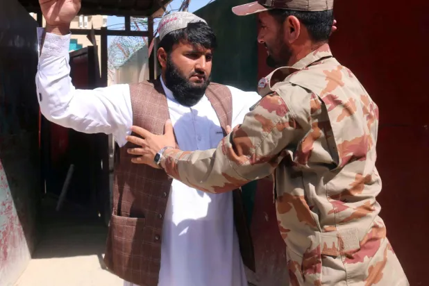 جندي باكستاني يفتش شخصاً أثناء الدخول عند الحدود الباكستانية الأفغانية في تشامان باكستان الثلاثاء (إ.ب.أ)