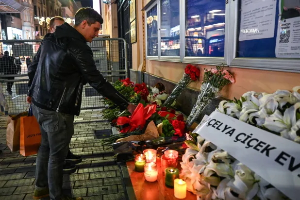 رجل يضع زهرة خارج القنصلية الروسية في إسطنبول تأبيناً لضحايا الهجوم المميت (أ.ف.ب)