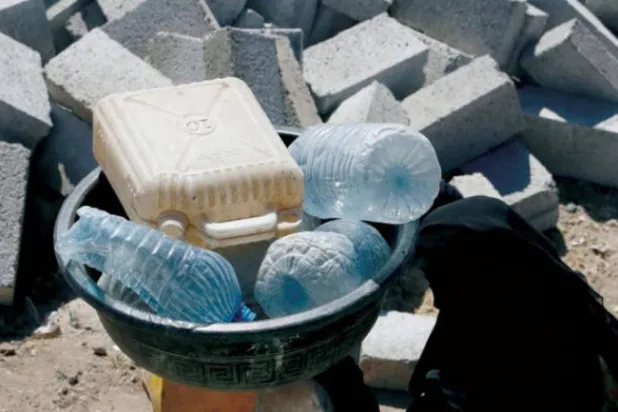 A displaced Yemeni woman in Sanaa carries cans to fill water tanks (EPA)